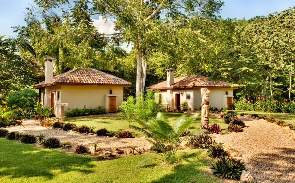 Two quaint cottages surrounded by lush greenery and a well-maintained garden.