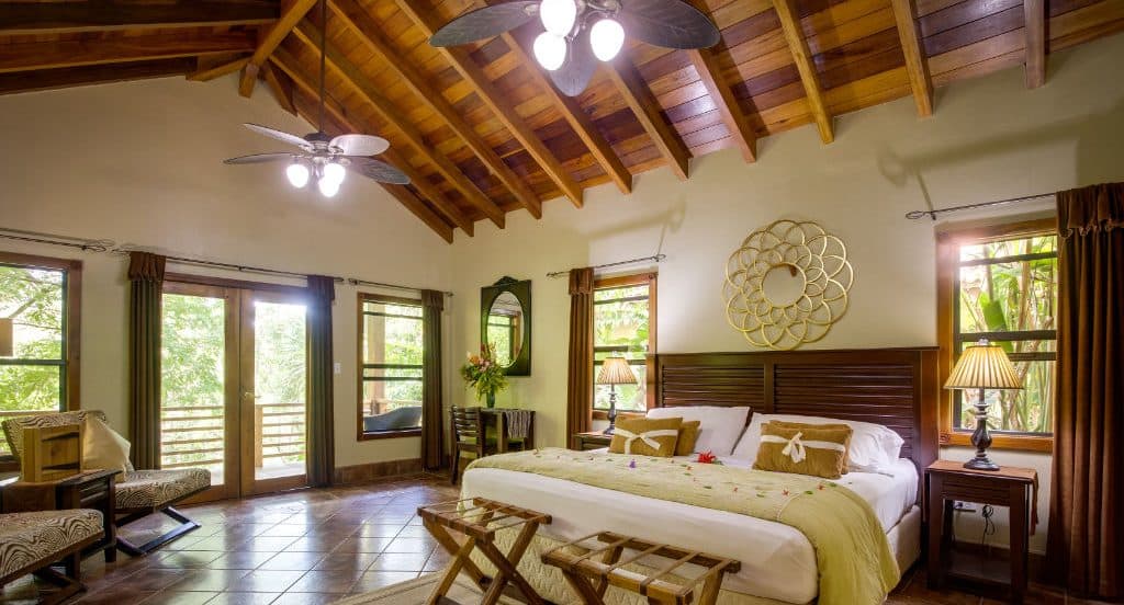 Bright and inviting bedroom with wooden ceiling, large windows, and cozy furnishings.