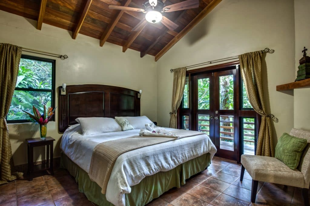 Cozy bedroom featuring a double bed, natural light from large windows, and tropical decor.