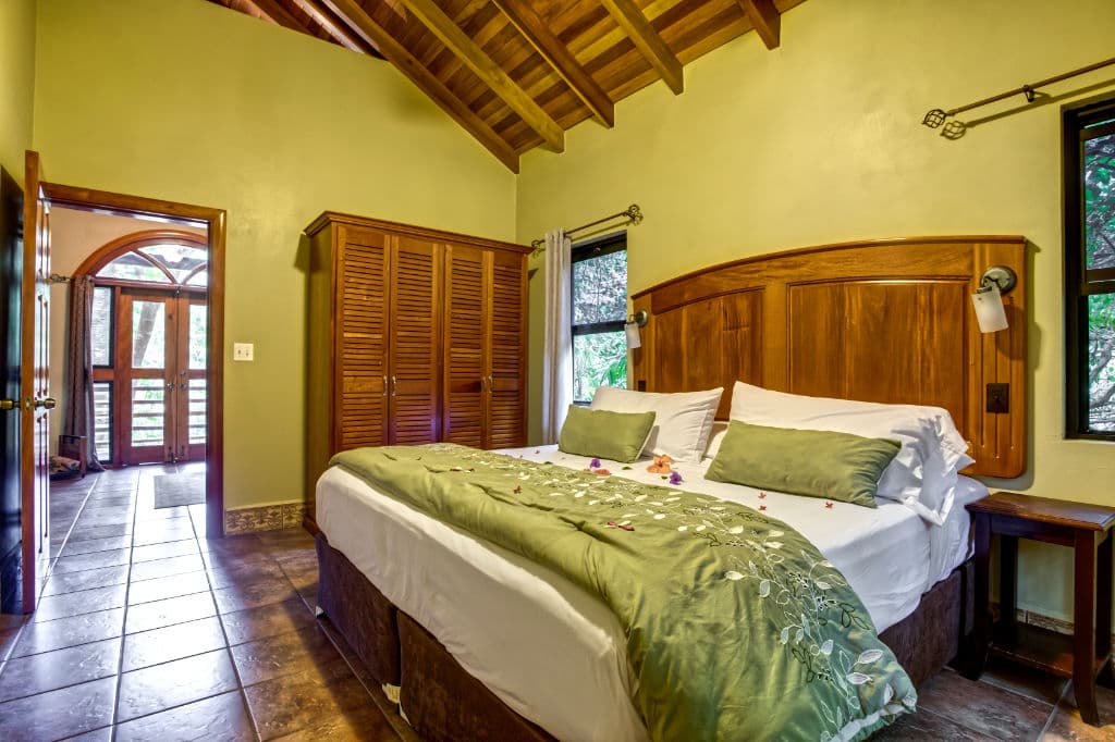 A cozy bedroom featuring a wooden bed with green bedding, ornate decor, and access to a balcony.